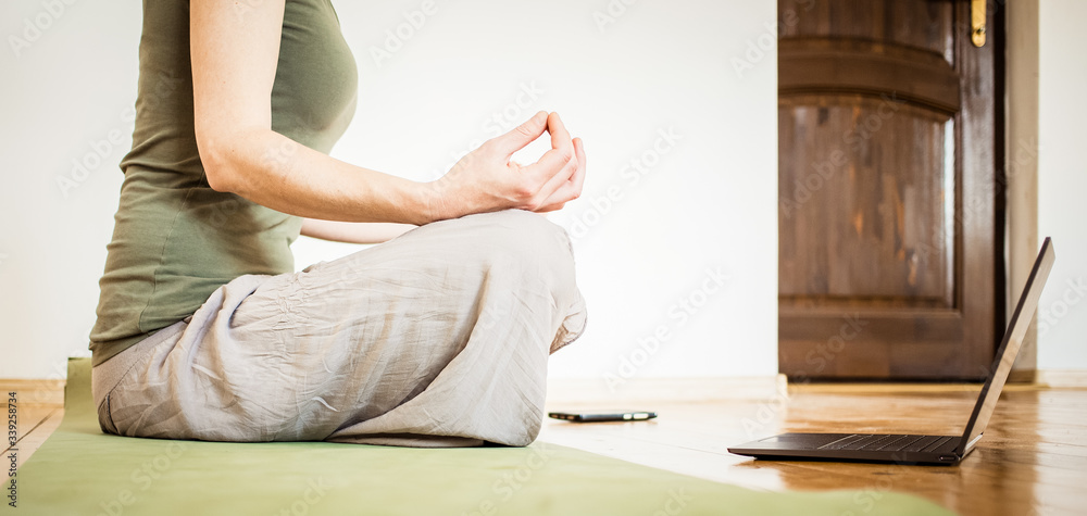 woman with laptop doing yoga at home coronavirus