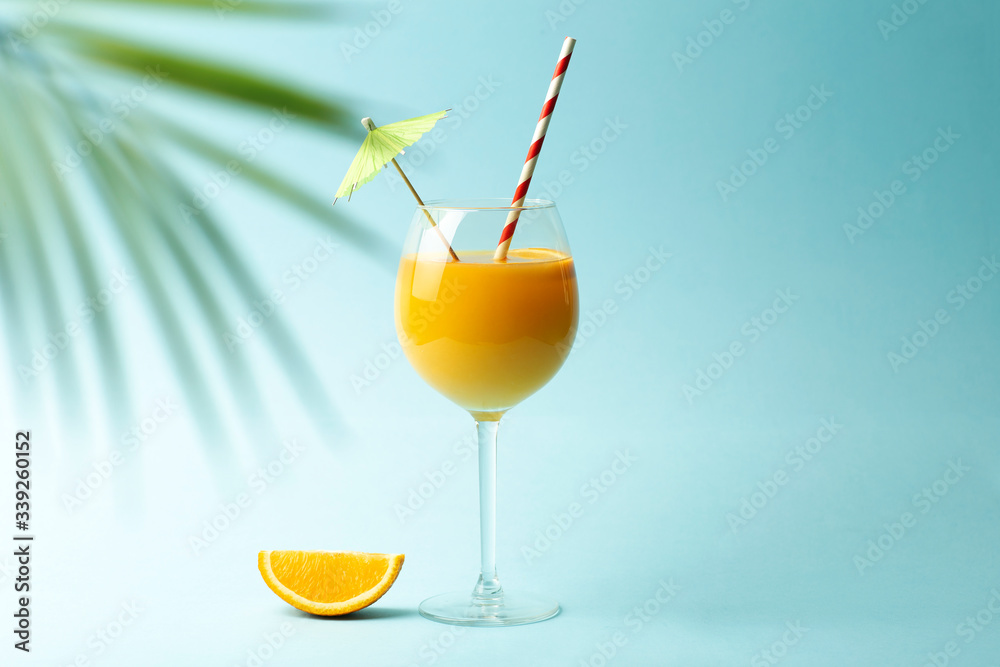 Summer drinks concept. Orange juice in a glass cup on a colored blue background. Tropical summer minimal background Summer drinks concept. Orange juice in a glass cup on a colored blue background. Tropical summer minimal background