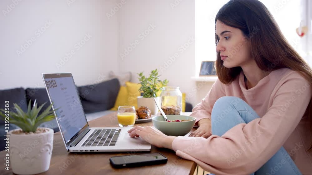 Young woman with breakfast using laptop at home, quarantine concept. Young woman with breakfast using laptop at home, quarantine concept.