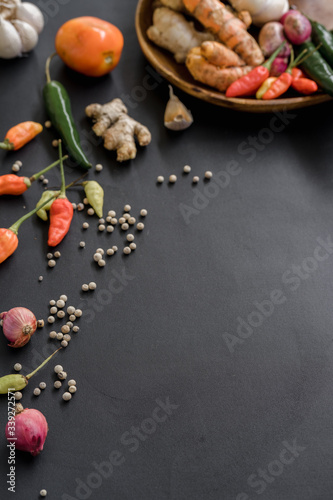 Basic ingredients of seasoning in a wooden plate. Some spices photographed scattered on a black background.