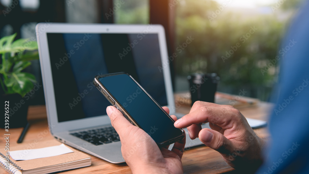 Mockup image of a man hands using smartphone with blank screen on wooden table.concept work form home, stay at home. Mockup image of a man hands using smartphone with blank screen on wooden table.concept work form home, stay at home.