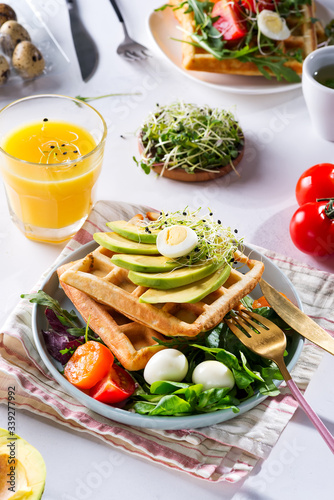 Breakfast time. Waffle with salad, egg, juice and avocados for breakfast. View from above.