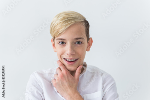 Close-up of teen boy with braces on teeth smiling on white background. Dentistry and teenager concept.