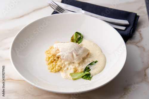 Fusion dish of baked cod with Beurre Blanc sauce, Israeli couscous and grilled vegetables