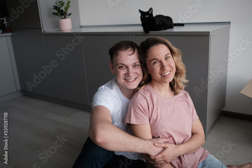 Cat in the house - a black cat sitting on a black table with kitchen desk and flower in a pot in the background..