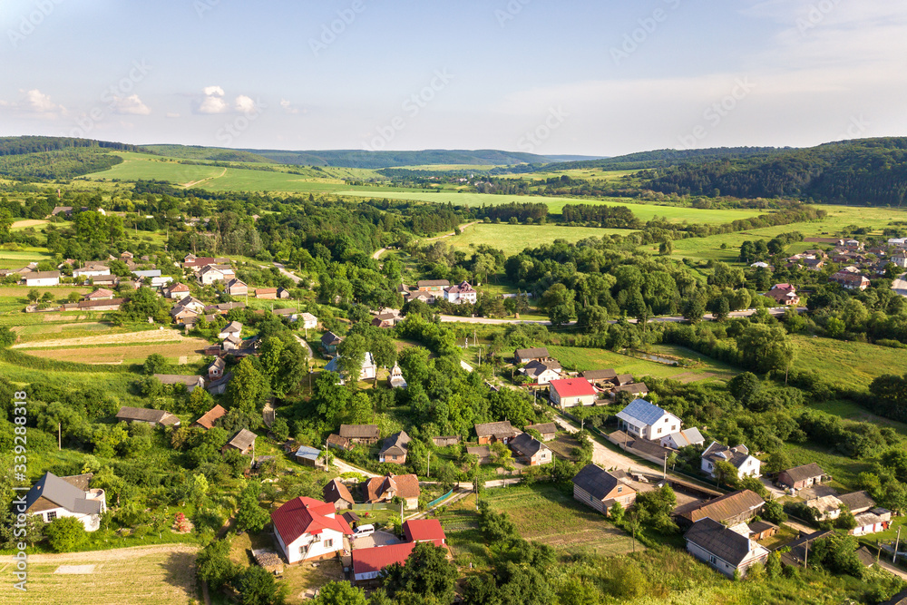 Aerial view of a small village win many houses and green agricultural fields in spring with fresh vegetation after seeding season on a warm sunny day. Aerial view of a small village win many houses and green agricultural fields in spring with fresh vegetation after seeding season on a warm sunny day.