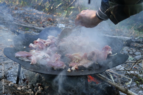 fry meat outdoors, a cast-iron frying pan on a fire,