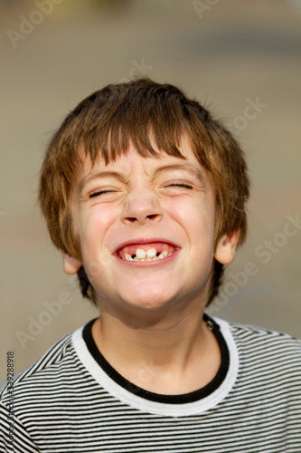 Portrait of handsome young boy smiling and showing his teeth outdoors