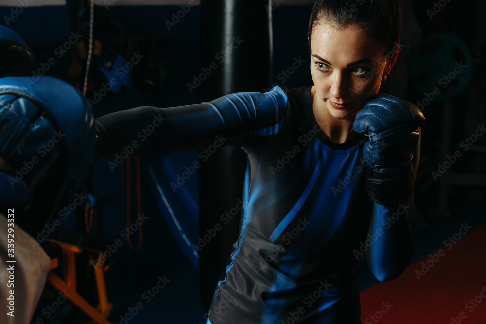 Young white sports woman, engaged in sports with the trainer in a hall. The concept of self-defense, sports and boxing, aggressive and evil attack.