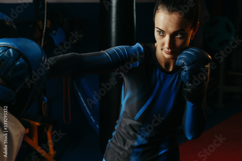 Young white sports woman, engaged in sports with the trainer in a hall. The concept of self-defense, sports and boxing, aggressive and evil attack. © Кирилл Горшков