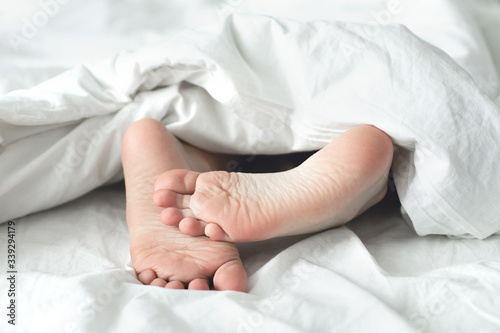 Child`s heels under blanket on bed. Stay home. Isolation, quarantine concept
