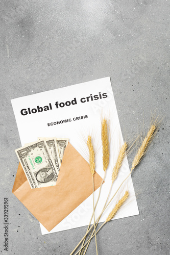 Economic crisis. Three dollars in an envelope, ears of corn, and a piece of paper with the words global food crisis on a gray background.Concept of the global financial crisis. Lack of money for food photo