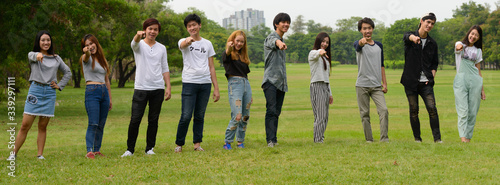 Happy young group of friends pointing at camera together at the park