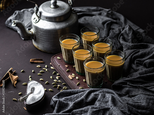 Indian chai in glass cups with metal kettle and other masalas to make the tea photo