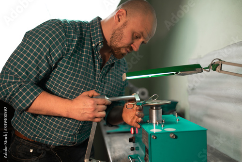 Master sharpens scissors on special equipment for sharpening tool