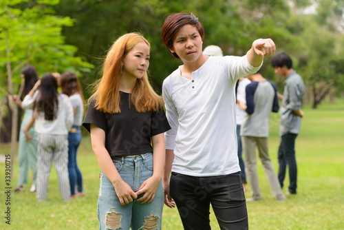 Young Asian couple together with friends at the park