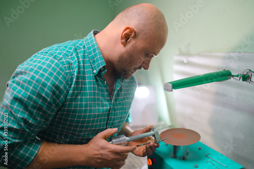 Master sharpens scissors on special equipment for sharpening tool