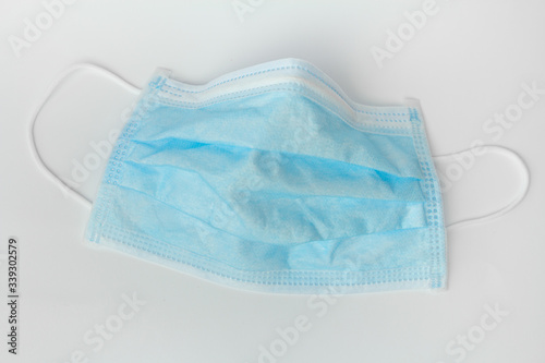 Used surgical mask on a blue background. Coronavirus prevention.