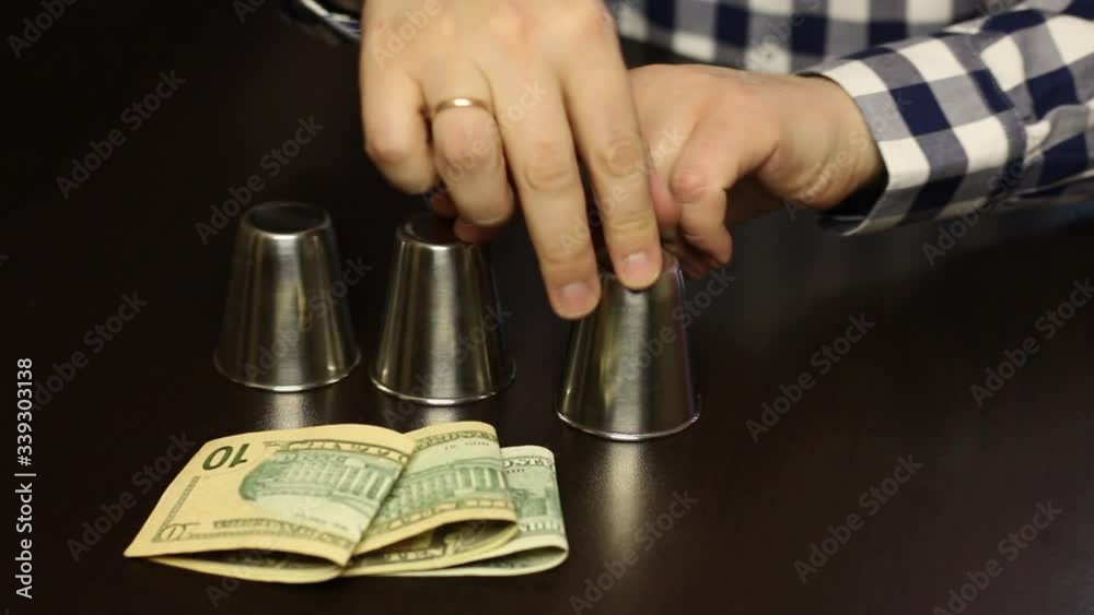 Thimblerig. Lead moves the thimbles. Loses, and gives his wedding ring. Close-up shot. Thimblerig. Lead moves the thimbles. Loses, and gives his wedding ring. Close-up shot.