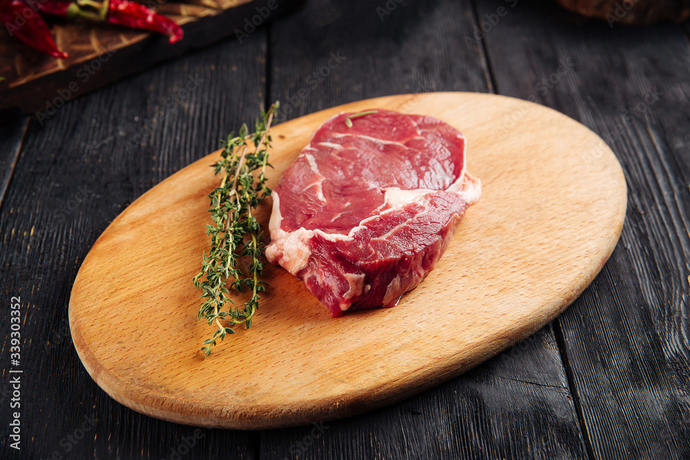 Side view on piece of fresh raw meat for cooking steak with sprigs of rosemary on a wooden board, horizontal Side view on piece of fresh raw meat for cooking steak with sprigs of rosemary on a wooden board, horizontal