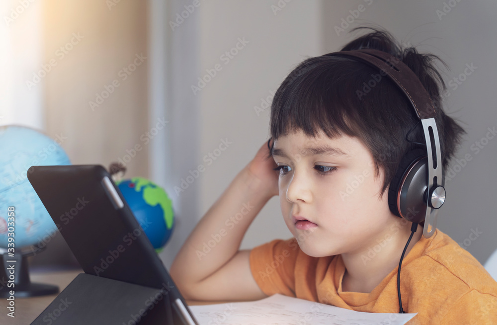 Kid self isolation using tablet for his homework,Child doing using digital tablet searching information on internet during covid 19 lock down,Home schooling,Social Distance,E-learning online education Kid self isolation using tablet for his homework,Child doing using digital tablet searching information on internet during covid 19 lock down,Home schooling,Social Distance,E-learning online education