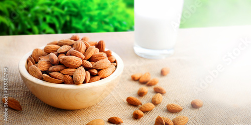 Almonds or nuts in brown bowl with almond milk on background.