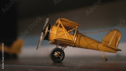 Miniature metallic airplane toy on a wooden shelf. Close up on childhood decorative toys. Panning left with revealing. Selective focus.