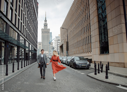 tourist couple in big city. The guy with the girl is hugging and happy. Girl in red dress kissing boy.