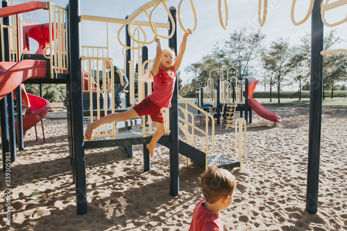 Foto Young Caucasian girl hanging on monkey bars in park on a playground