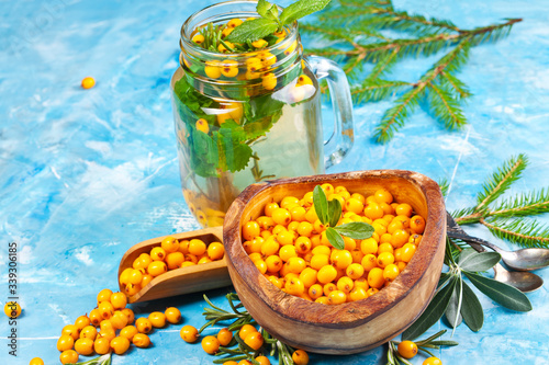 Sea buckthorn berries on wooden bowl on bright background photo