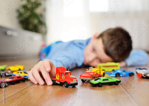 Tableau sur toile a small child preschool boy playing toy cars on the wooden floor in a bright roo