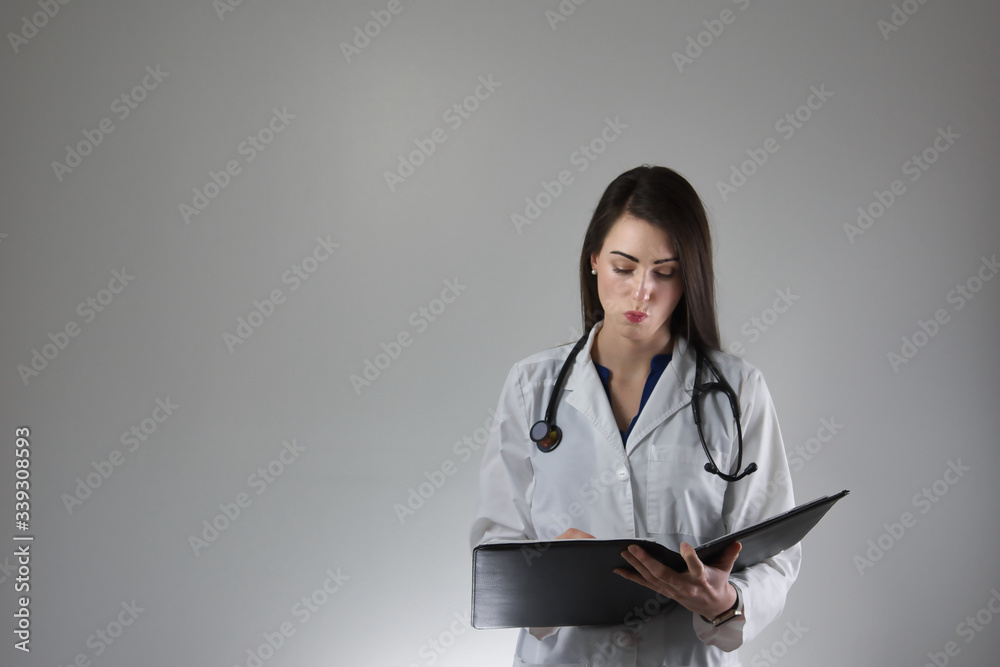 Female healthcare professional making note in patient's charge isolated on grey background Female healthcare professional making note in patient's charge isolated on grey background