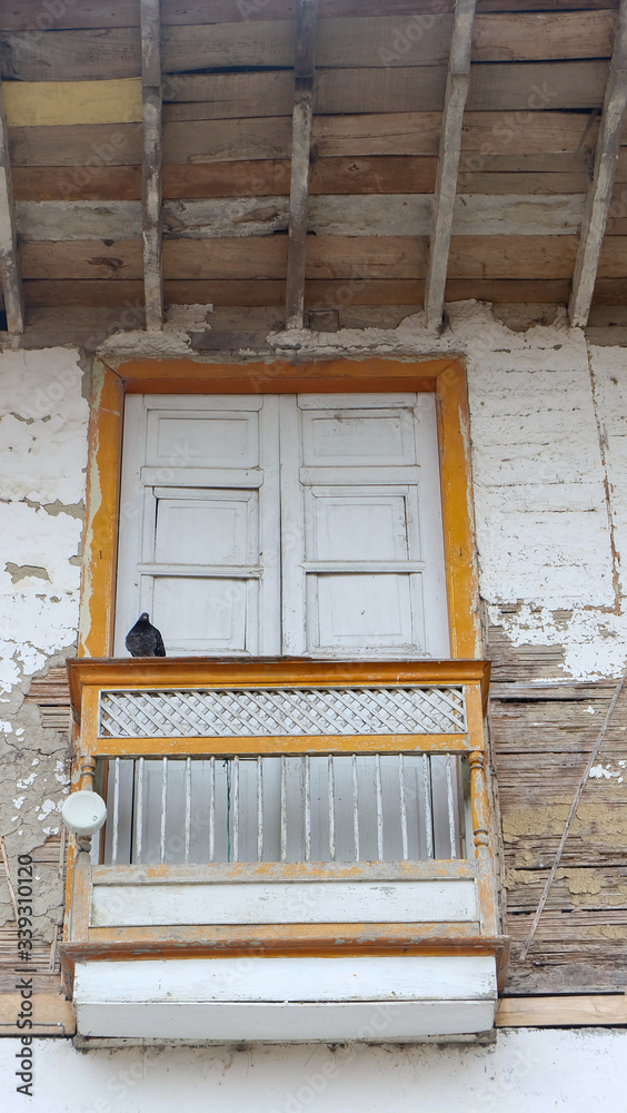 white window with small porch in old house built of bahareque and wood