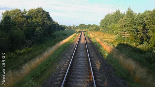 Back view of railroad and a beautiful green nature from a train passing on countryside land. Railroad travel or railway tourism concept. Slow motion back view 4K video.