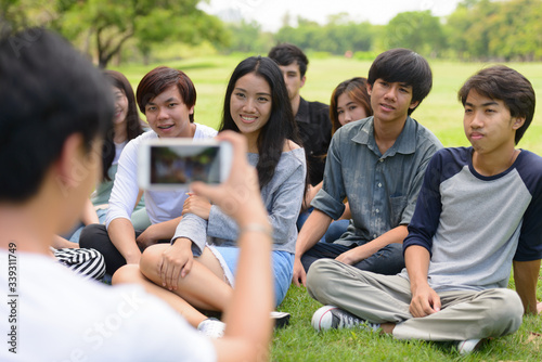 Happy young group of friends taking picture with phone together at the park