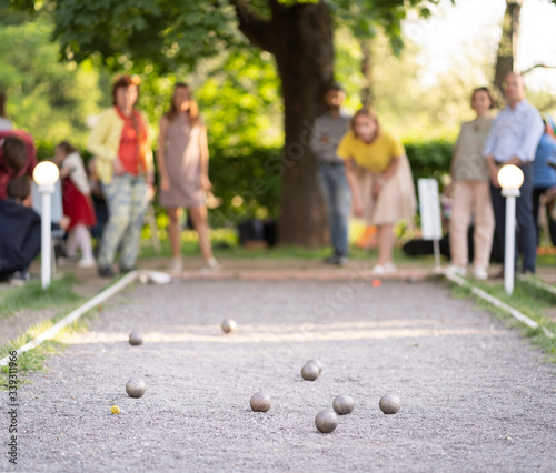 Eldery friends playing petanque in city park woman throwing a ball outdoor summer activity