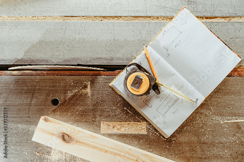 tools for planning a wooden product: meter, pencil and workbook on a workbench in a joinery