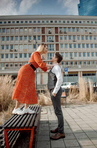 tourist couple in big city. The guy with the girl is hugging and happy. Girl in red dress kissing boy.