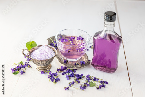 Fototapet Cup of herbal violet violetta odorata tea with fresh spring blossom petals flowe