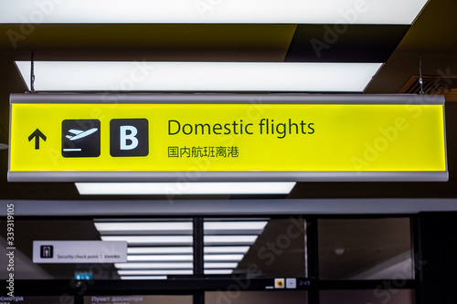 Bright illuminated yellow and black airport signs with arrows and plane icons and the title in Chinese: "Domestic flights".