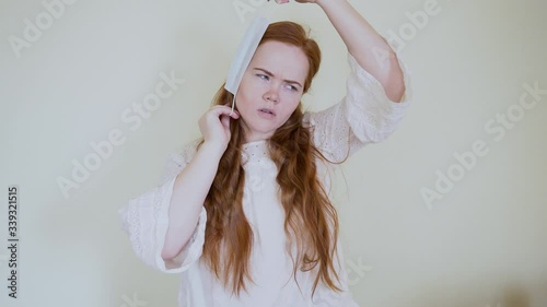 the girl wears a mask against coronavirus, microbes, diseases, on uniform background.she has red hair, a white jacket, and pretty .A blue mask covers the face, nose and mouth.he's wearing plaid shirt