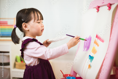toddler girl practice watercolor paiting at home agianst white background