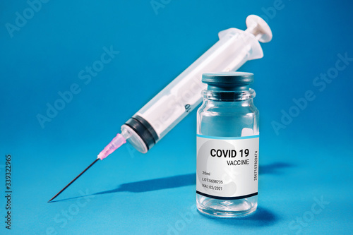 Coronavirus vaccination concept. Covid-19 medicine bottle with syringe, isolated against blue background.