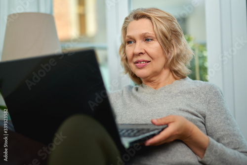 Mature woman working online sitting on a sofa in an home.