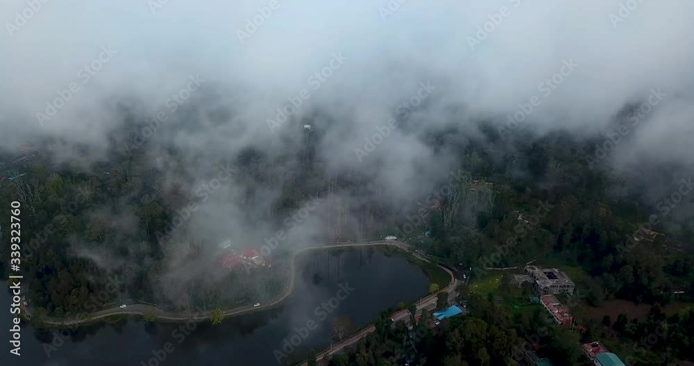 Lake in tropical forest nature in Kodaikanal Kerala India under the foggy clouds with road trip around the mountain lake on green hills Lake in tropical forest nature in Kodaikanal Kerala India under the foggy clouds with road trip around the mountain lake on green hills