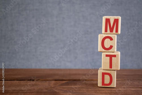 Abbreviation MCTD (Mixed connective tissue disease) text acronym on wooden cubes on dark wooden backround. Medicine concept.