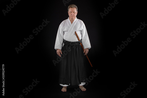 Portrait aikido master wearing traditional samurai hakama clothes with boken in hands. on black Background photo