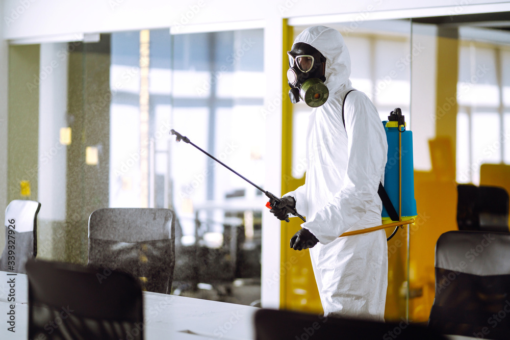 Disinfecting of office to prevent COVID-19, Man in protective hazmat suit with  with spray chemicals to preventing the spread of coronavirus, pandemic in quarantine city. Cleaning concept.