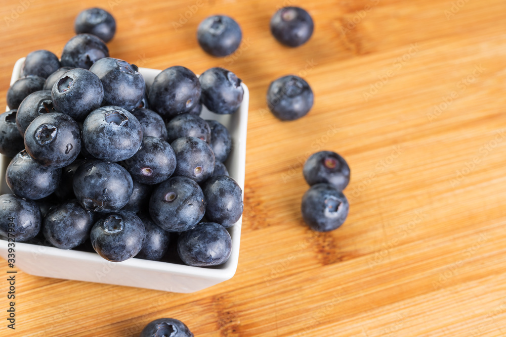 Fresh blueberry in white plate photographed against wooden background Fresh blueberry in white plate photographed against wooden background