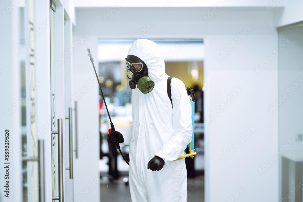 Disinfecting of office to prevent COVID-19, Man in protective hazmat suit with with spray chemicals to preventing the spread of coronavirus, pandemic in quarantine city. Cleaning concept. Disinfecting of office to prevent COVID-19, Man in protective hazmat suit with with spray chemicals to preventing the spread of coronavirus, pandemic in quarantine city. Cleaning concept.